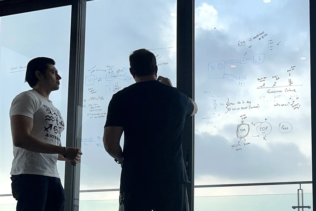 Two of the Squid founders working through architecture on a glass wall